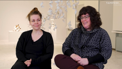 Kakis naista istuu taidenäyttelytilassa