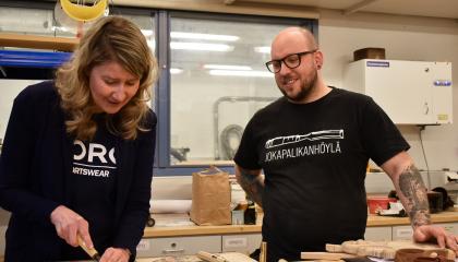 Kaksi henkilöä puukäsityöluokassa talttatyössä.