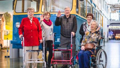 Viisi ikäihmistä seisoo vanhan kaupunkibussin edessä