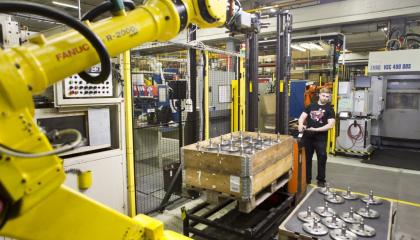 Mies siirtää pumppukärryllä osia tuotantolaitoksessa