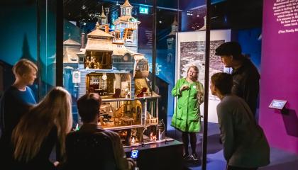 Ihmisiä ja opas Muumi-talo kuvaelman ympärillä Muumimuseossa.