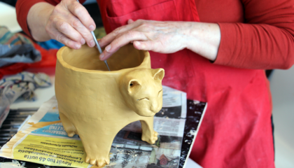 Henkilön kädet, jotka viimeistelevät keramiikkatyötä.