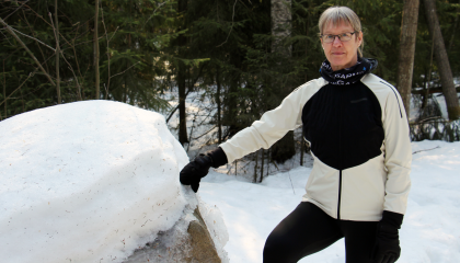 Henkilö metsässä kiven vieressä. Pia Nykänen.