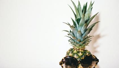 Kuvassa on ananas, jolla on aurinkolasit