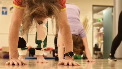 Kaksi henkilöä jooga-asanoissa liikuntasalissa.