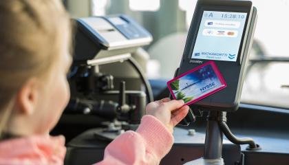 Tyttö käyttää matkakortin bussin lukijalaitteessa.