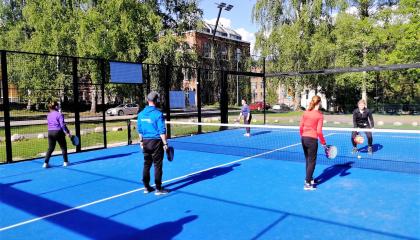 Nuoret pelaavat padelia liikunnanohjaajan kanssa.