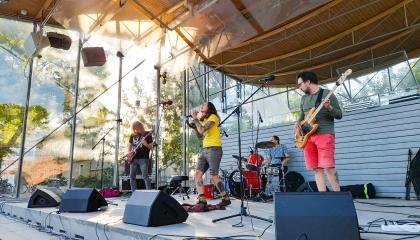 Laulaja ja soittajat lavalla puistokonsertissa.