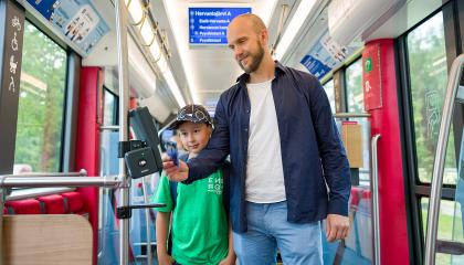 Mies ja poika leimaavat liput ratikassa