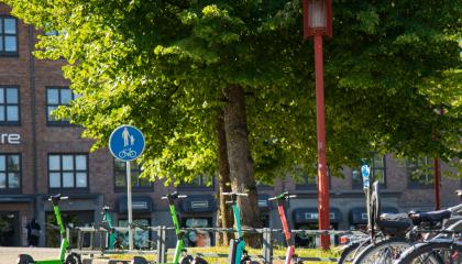 Pysäköityjä sähköpotkulautoja polkupyörätelineissä.