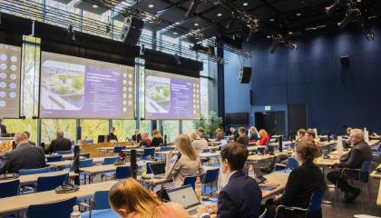 Tampereen kaupunginvaltuusto istuu kokouksessaan Tampere-talossa. Salin edessä on kolme suurta näyttöä.