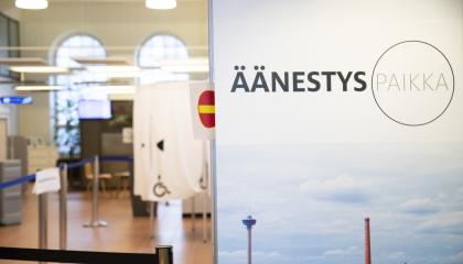 Etualalla panoraamakuva Tampereesta ja teksti Äänestyspaikka. Taustalla äänestyskoppeja.