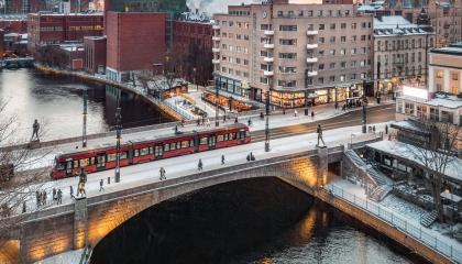 Raitiovaunu talvisella Hämeensillalla, taustalla savua piipuista kellertävälle taivaalle.