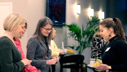 Neljä henkilöä tutkii pöydällä olevia työpajan materiaaleja kokoustilassa.