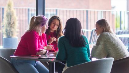 Neljä naista ideoimassa pöydän ääressä.