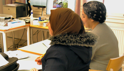 Kaksi henkilöä opiskelee pulpetin ääressä luokkahuoneessa.