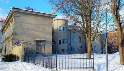 Vaaleapintainen Frenckellin konttori talvisessa maisemassa, aidatulla pihalla vanhoja isoja puita.