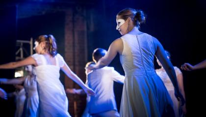 Tanssijoita lavalla vaaleat maskit silmillään.