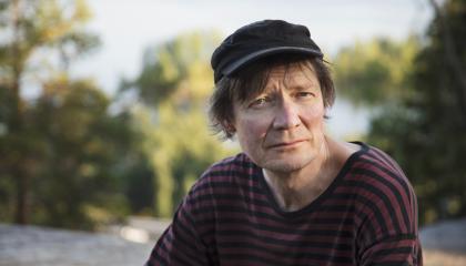 Henkilö istuu kalliolla, jonka taustalla on metsää.