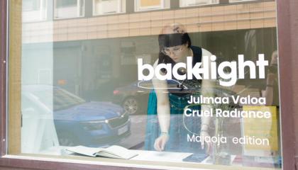 Nuori nainen on liiketilan näyteikkunassa. Hän tekee töitä.