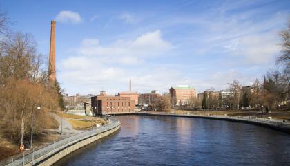 Tammerkoski keväisessä maisemassa. Etualalla vettä ja taustalla rakennuksia.