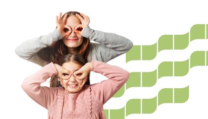 Äiti seisoo tyttärensä takana, ja kumpikin hymyilee. He ovat tehneet sormillaan kiikarit, joiden läpi he katsovat kohti katsojaa.