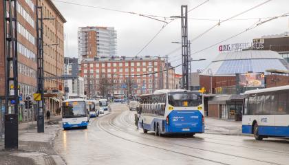Useita busseja liikenteessä kadulla.