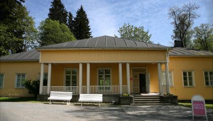 Keltainen rakennus, jossa avokuisti. Kuistissa neljä valkoista paripylvästä.