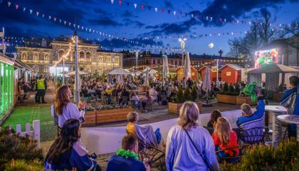 Torille jääkiekkopaidoissa kerääntyneitä ihmisiä tummenevassa illassa.