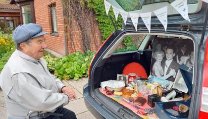 Harmaatakkinen mies katselee auton tavaratilaan aseteltua Peräkonttimuseon näyttelyä.