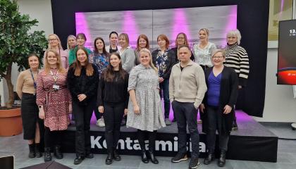 Ihmiset hymyilevät ryhmäkuvassa.