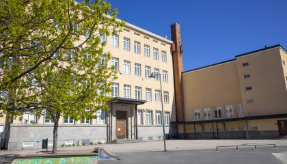 Nekalan koulu on kellertävä nelikerroksinen entinen koulurakennus, jonka pihamaalla on lehtipuita.