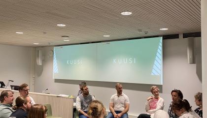 Henkilöt istuvat reingissä ja keskustelevat.