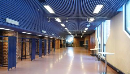 Käytävä, jolla naulakoita ja muutama pystypöytä.