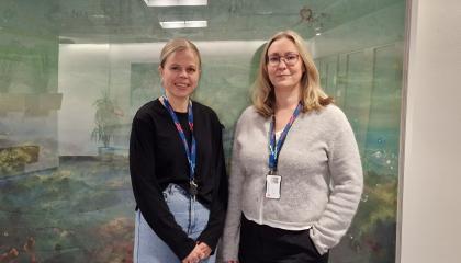 Kaksi hymyilevää naista seisomassa.