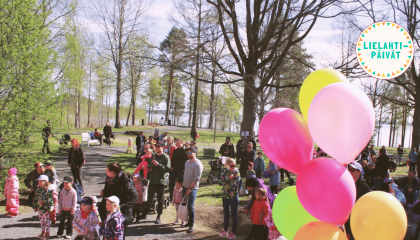 Runsaslukuinen ihmisjoukko viettää aikaa ulkona puistossa.