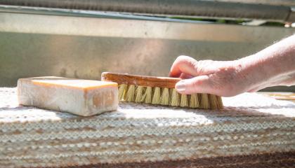 Mäntysaippua, pesuharja ja matto matonpesupaikalla. 