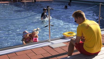 Uima-altaassa pieniä lapsia uimassa ja uimavalvoja 