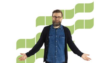 Hymyilevä partainen mies takanaan vihreitä aaltokuvioita.