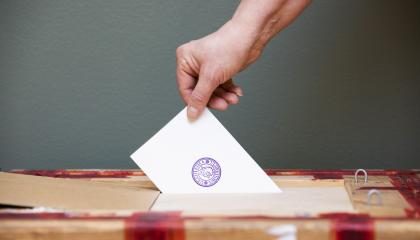 Käsi, joka laittaa äänestyslippua vaaliuurnaan.