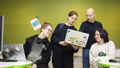 Teknillisen lukion neljä opiskelijaa katsoo tietokoneen ruutua yhdessä.