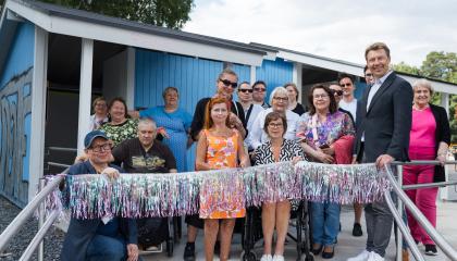 Ihmisiä Pyynikin esteettömän uimarannan avajaisissa. Oranssiasuinen vammaisneuvoston puheenjohtaja on leikkaamassa hopealamenauhaa.