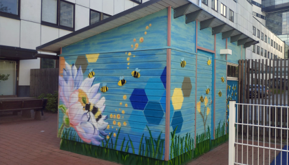 Laudoista tehty vaja, jonka seinillä kukka- ja hyönteisaiheisia maalauksia.