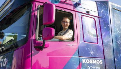 Kuljettaja katsoo purppuran värisen kuorma-auton ikkunasta.