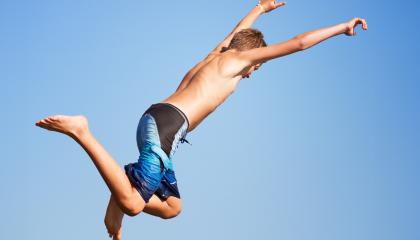 Henkilö uimahousuissa hyppäämässä ilmassa.