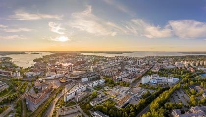 Tampereen kaupungista ilmakuva, jossa näkyy keskustan rakennuksia ja puistoja sekä taustalla Näsijärvi ja Pyhäjärvi.