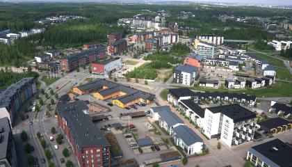 Kuvassa kaupunginosan rakennuksia, keskellä vihreä aukioalue.
