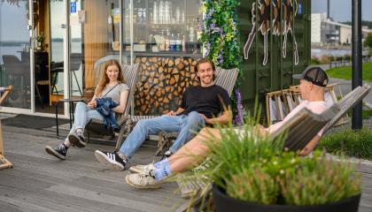 Kolme nuorta ihmistä kesällä istuskelemassa Ranta-Tampellassa kioskin edessä. 