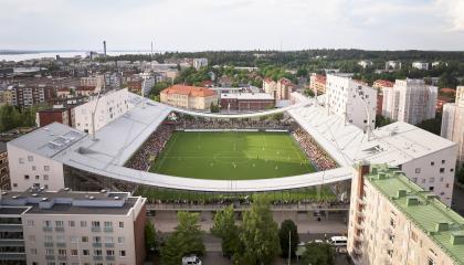 Tammelan Stadion kuvatuna ilmasta käsin niin että näkyy pelikenttä asuinkerrostalojen keskellä ja kuvassa korostuu stadionin muoto sekä kaarevat päätyrakenteet.