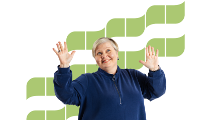 Hymyilevällä naisella on kädet iloisesti pystyssä.